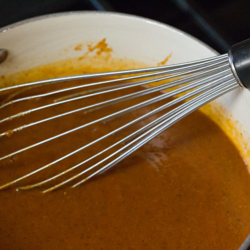 enchilada sauce in a pot with a whisk