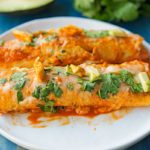 enchiladas with avocado and cilantro on a white plate